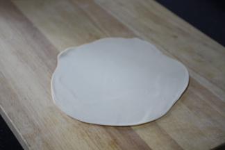 将另一个面团盖在上面，用擀面杖擀成薄面皮。