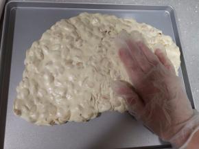 5将牛轧糖倒入学厨牛轧糖专用不粘烤盘，带上一次性手套反复按压，将牛轧糖充分包裹花生仁