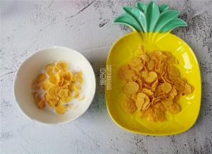 首先牛奶倒入碗中，取适量的玉米片放入。