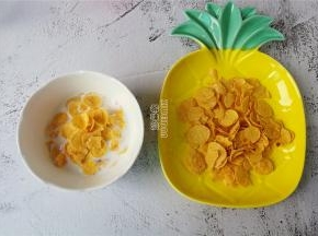 首先牛奶倒入碗中，取适量的玉米片放入。
