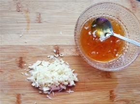 首先鸡中翅洗净划上几刀，把蒜瓣切成蒜蓉，拌入柚子蜂蜜中备用。