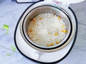 把沥干的混合好的梗米倒入甑子中，用饭铲压压平。