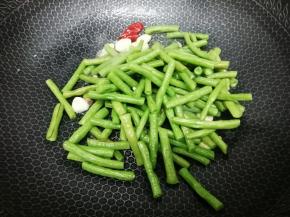 然后把焯好的的长豆角放入锅中，再加入少许的盐，翻炒片刻