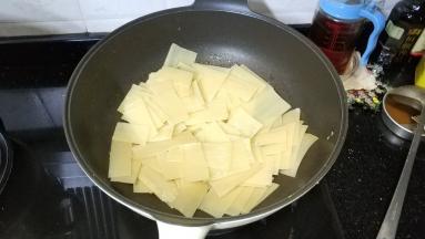 锅里热油放入烤冷面煎炒