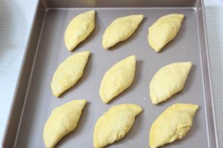 将蛋挞皮对折捏起来，放入烤盘中。薄薄的刷一层鸡蛋液，撒一点黑芝麻。