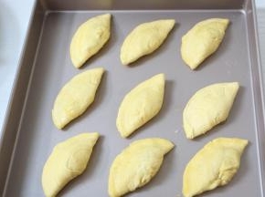 将蛋挞皮对折捏起来，放入烤盘中。薄薄的刷一层鸡蛋液，撒一点黑芝麻。