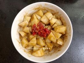 切好的土豆丁装进碗中，把生抽，蚝油，辣椒酱一起放进碗中，全部搅拌均匀腌制一会