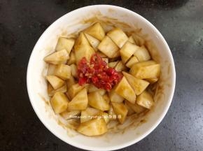 切好的土豆丁装进碗中，把生抽，蚝油，辣椒酱一起放进碗中，全部搅拌均匀腌制一会