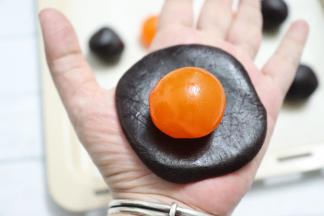 把豆沙馅搓成一个球，压扁，包住蛋黄。