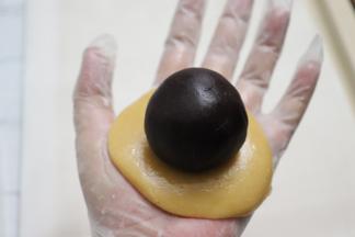 .取出一块面团，压扁，放上准备好的馅料球。