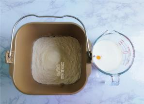 首先把面粉和奶粉倒入面包桶中，鸡蛋液+牛奶称出300克也可。