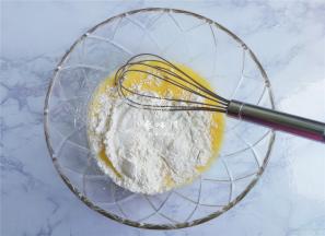 把低筋面粉筛入混合好的液体中，用打蛋器写“米”字的混合面粉，无干粉，无颗粒即可。