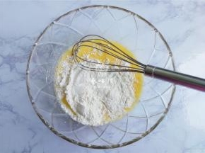 把低筋面粉筛入混合好的液体中，用打蛋器写“米”字的混合面粉，无干粉，无颗粒即可。