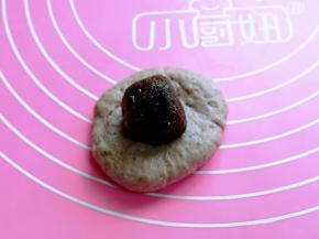 取一块面团，用手按压放上豆沙馅。