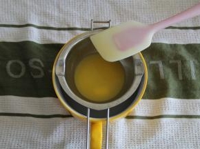 2、主料中的黄油直接装入融化碗里，架在一碗温热的水上，静置一会，等黄油差不多融化，用刮刀搅拌均匀，保温备用。