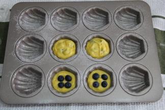 剪口、挤入模具，8-9分满。可以直接挤八分满，然后将蓝莓直接压入面糊中。也可以挤一半面糊，然后压入蓝莓，再挤上一点面糊盖住蓝莓。皆可。然后震一下模具。