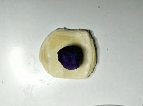 取一个酥皮按扁，包入紫薯馅