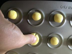 搓好的圆球用大拇指摁一下，不要太用力，压扁圆球的一半即可。