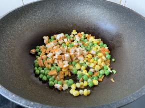 放入胡萝卜、豌豆、玉米、鸡肉丁，翻炒1分钟。