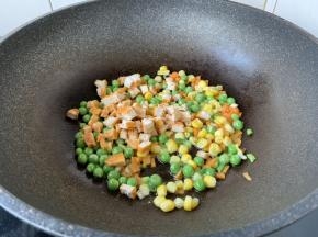 放入胡萝卜、豌豆、玉米、鸡肉丁，翻炒1分钟。