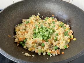 放入米饭，翻炒均匀，不停的翻炒，翻炒至米饭粒干爽，然后放入黄瓜丁，再次翻炒均匀。