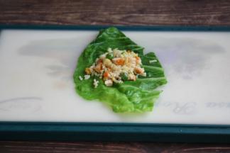 铺上一张焯过水的包菜，在包菜上放上适量的鸡肉什锦炒饭。