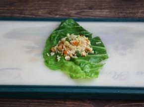 铺上一张焯过水的包菜，在包菜上放上适量的鸡肉什锦炒饭。