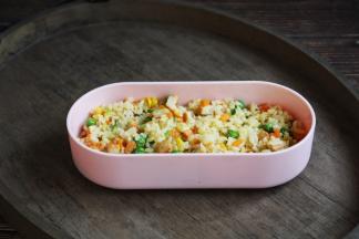 将一部分鸡肉什锦炒米饭铺在便当盒的底部。