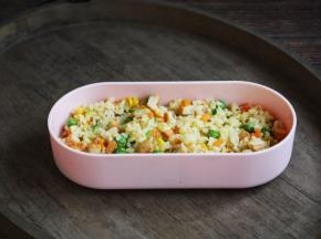 将一部分鸡肉什锦炒米饭铺在便当盒的底部。