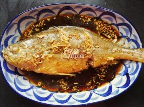 黄花鱼蒸熟后放入鱼盘中倒入备好的酱汁，让鱼肉吸收点汁水。
