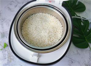 把浸泡好的糯米倒入甑子中，倒入适量的清水蒸制。