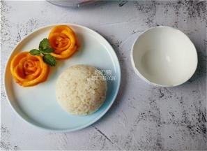 用芒果摆点造型，米饭盛入碗中倒扣在碗中，浇入少许椰浆搭配即可。