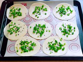 擀好刷过油的饺子皮摆放在烤盘中，撒上黑白芝麻，撒上盐。