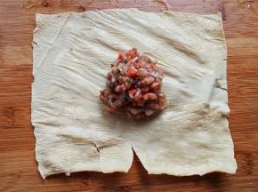 把泡软的豆腐皮拿出来，用厨房纸吸干水分，挖一勺肉馅放入豆腐皮中。