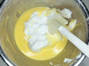 取三分之一蛋白加入蛋黄糊中，用刮刀翻拌均匀。不要画圈搅拌。
