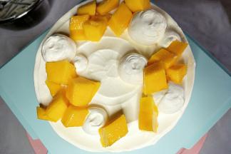 在蛋糕面上放入芒果块，挤出奶油小圆做装饰