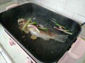 重新把煎好的鱼放入锅内，加入热水、料酒、葱头、姜片