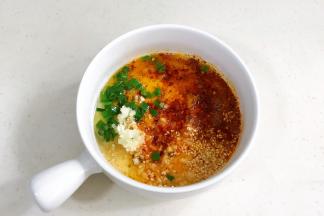 提前把白芝麻、蒜末、葱花和辣椒面放入碗内，把适量的食用油加热淋入其中。