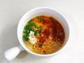 提前把白芝麻、蒜末、葱花和辣椒面放入碗内，把适量的食用油加热淋入其中。
