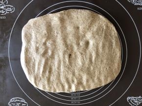 把面团放在揉面垫上按压排气。