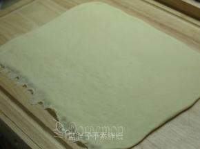 松弛好的面团排气，用擀面杖擀成长方形面团（30*25cm）。底端用手指压扁。