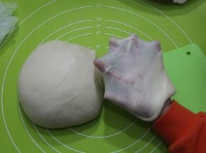 打好面团取出，两手握面团，向身体外侧折叠收圆，切一块下来，慢慢扯开就能看到薄薄的手套膜。