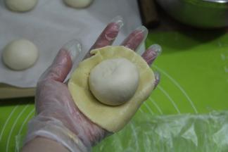 撕开保鲜袋，取下酥皮，放上滚圆的面团，光滑面接触酥皮，收口朝上。