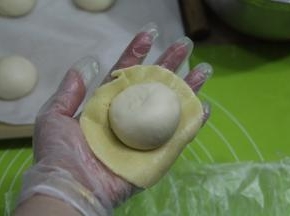 撕开保鲜袋，取下酥皮，放上滚圆的面团，光滑面接触酥皮，收口朝上。