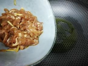 加入适量油把腌制好的肉片倒入锅中，快速的划开，炒到肉变色