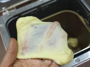 .除黄油外，将面团中的其它原材料按放入东菱面包机中，开启1个揉面程序。揉至面团光滑，能拉出厚膜。
