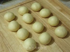 发酵好的面团按压拍打排气，平均分成12个面团，将它们都滚圆之后盖上保鲜膜松弛15分钟。