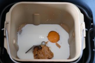 将牛奶、鸡蛋、花生酱倒入面包机的面包桶中，盐、糖对角放；