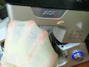 取出厨师机搅拌桶（没有厨师机也可以用面包机，或者手揉），放入牛奶、鸡蛋、盐、糖、高筋面粉、耐高糖酵母，装好搅拌桶，启动1档揉成团，继续启动4档搅拌8分钟后，加入黄油，继续搅拌到能够轻松拉出柔韧的薄膜状态。放回面包桶，盖上保鲜膜放在温暖处发酵。