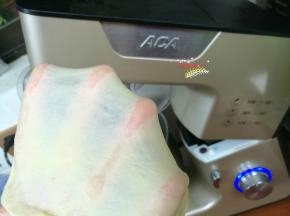 取出厨师机搅拌桶（没有厨师机也可以用面包机，或者手揉），放入牛奶、鸡蛋、盐、糖、高筋面粉、耐高糖酵母，装好搅拌桶，启动1档揉成团，继续启动4档搅拌8分钟后，加入黄油，继续搅拌到能够轻松拉出柔韧的薄膜状态。放回面包桶，盖上保鲜膜放在温暖处发酵。